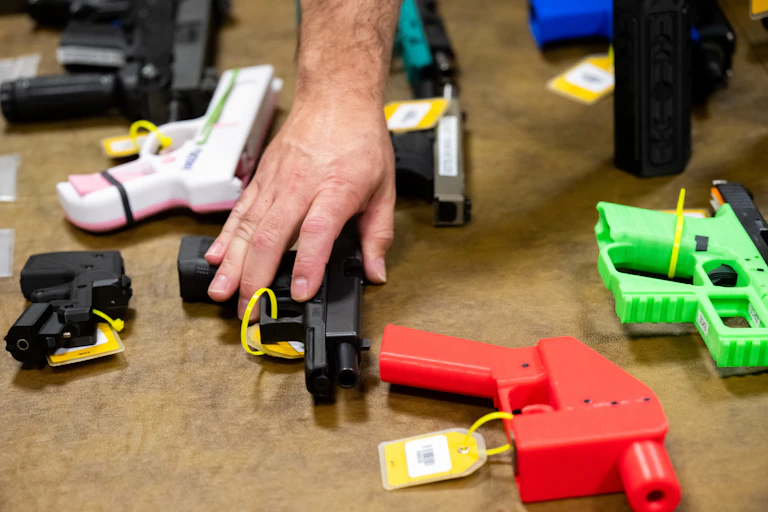 A group of firearms of different colors and materials.