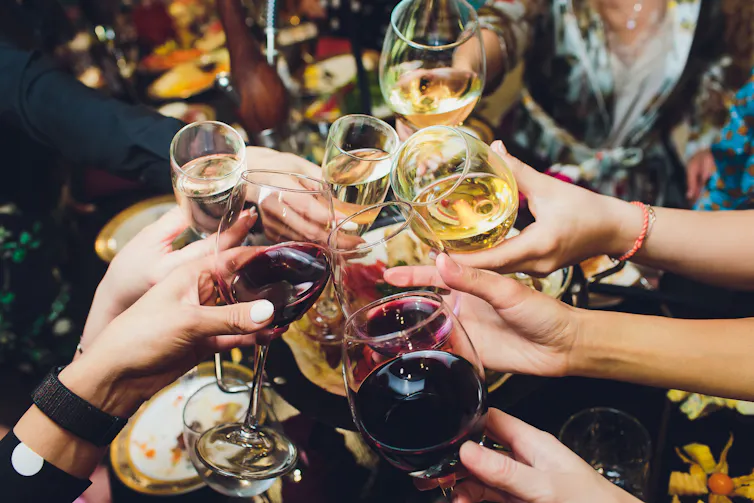 A bunch of people cheers their wine glasses.