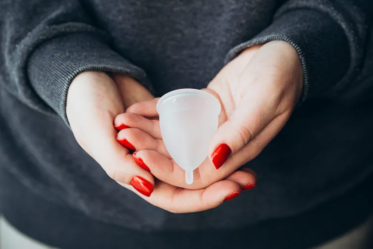 Hands holding a clear menstrual cup.