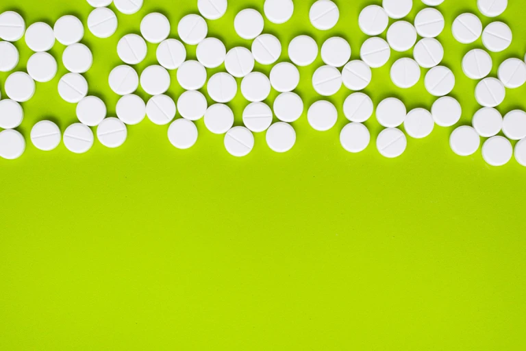 White paracetamol pills against lime green background