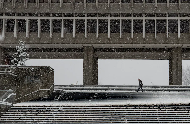 A figure crosses stairs in snow.