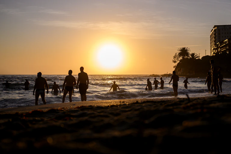 beachgoers in silhouette at sunrise