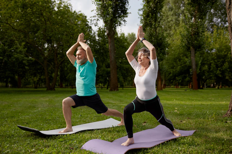 An older man and woman perform the warrior 1 pose.