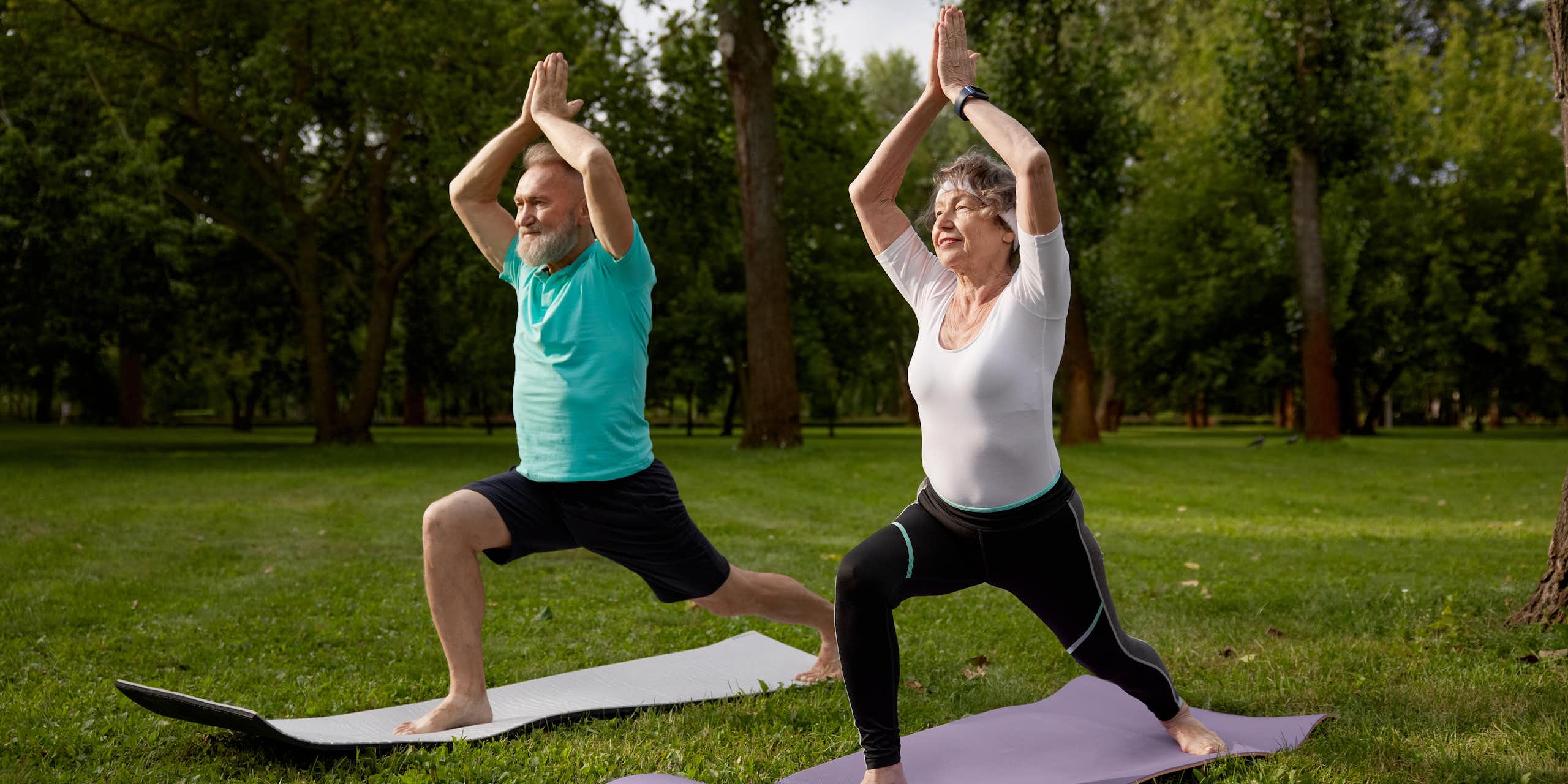 An older man and woman perform the warrior 1 pose.