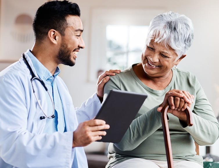 An older woman and a doctor looking at a tablet