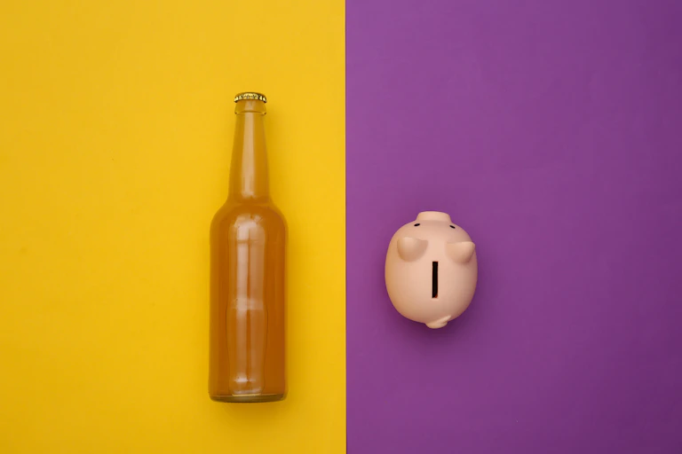 A bottle against a yellow background and a piggy bank against a purple background