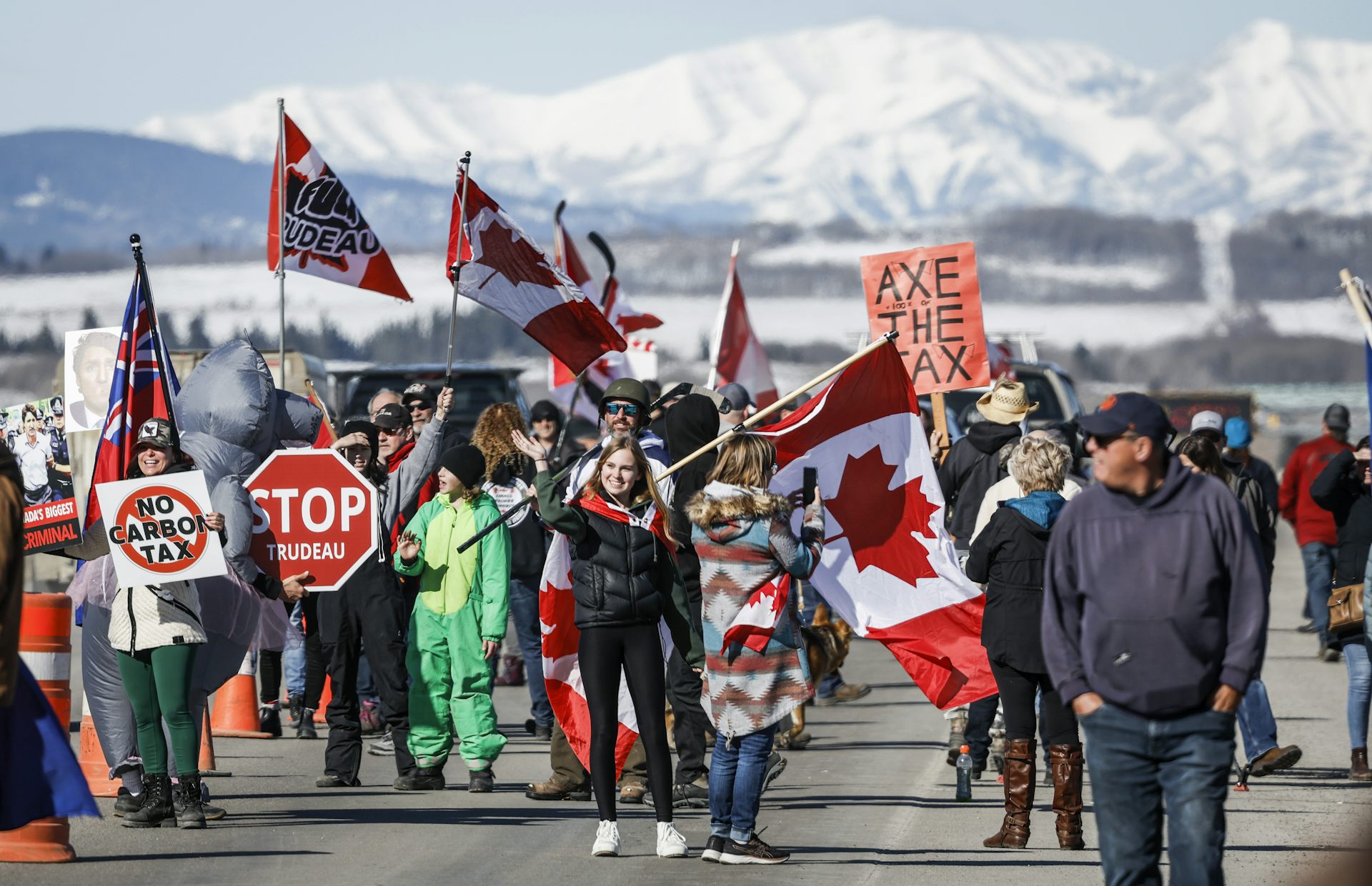 A group of people holding flags and signs walk in a road.