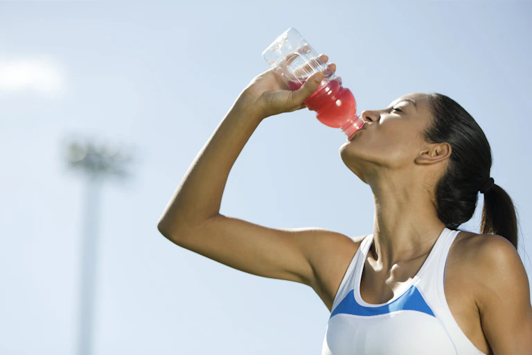 A woman drinking a sports drink.