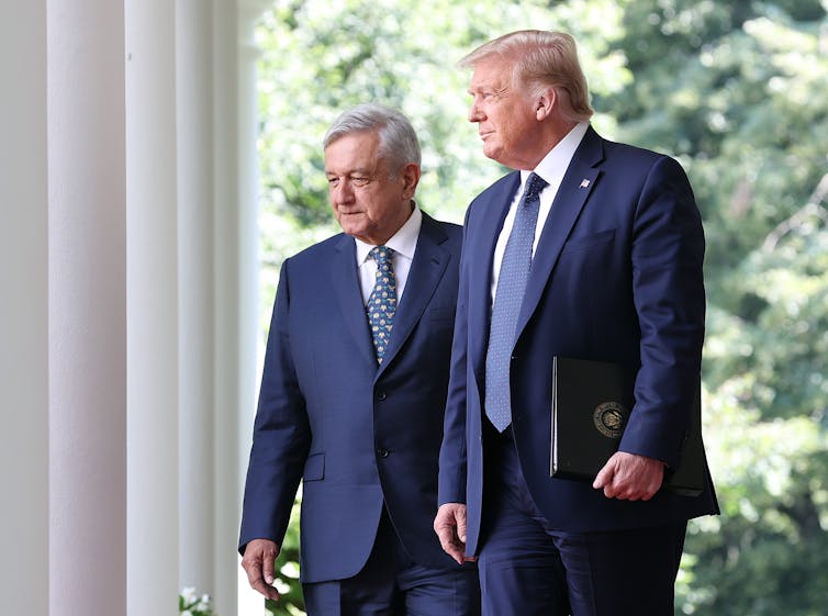 Two men in blue suits walk outside.