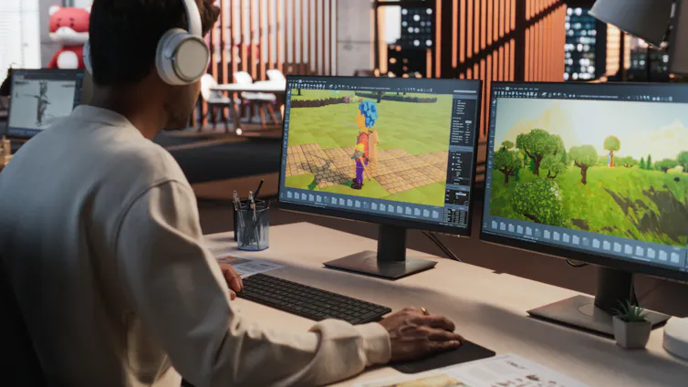 A person, seen from behind, working on a 3D modelling project on a computer