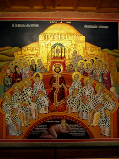 A jewel-toned religious painting of men with halos seated around a kingly figured in red robes, and one man in plainer clothes lying at the bottom.