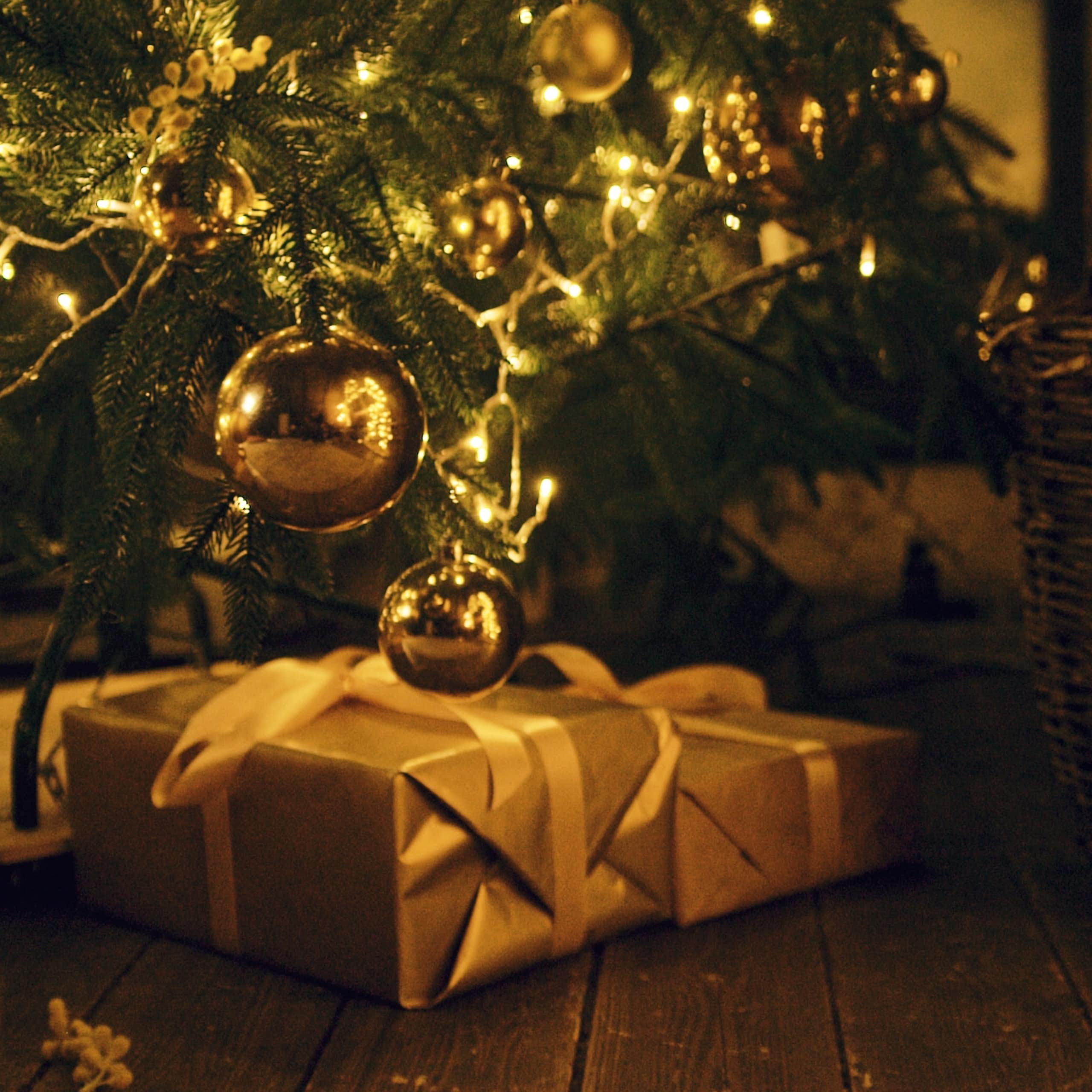 presents at the foot of a christmas tree. the light is golden.