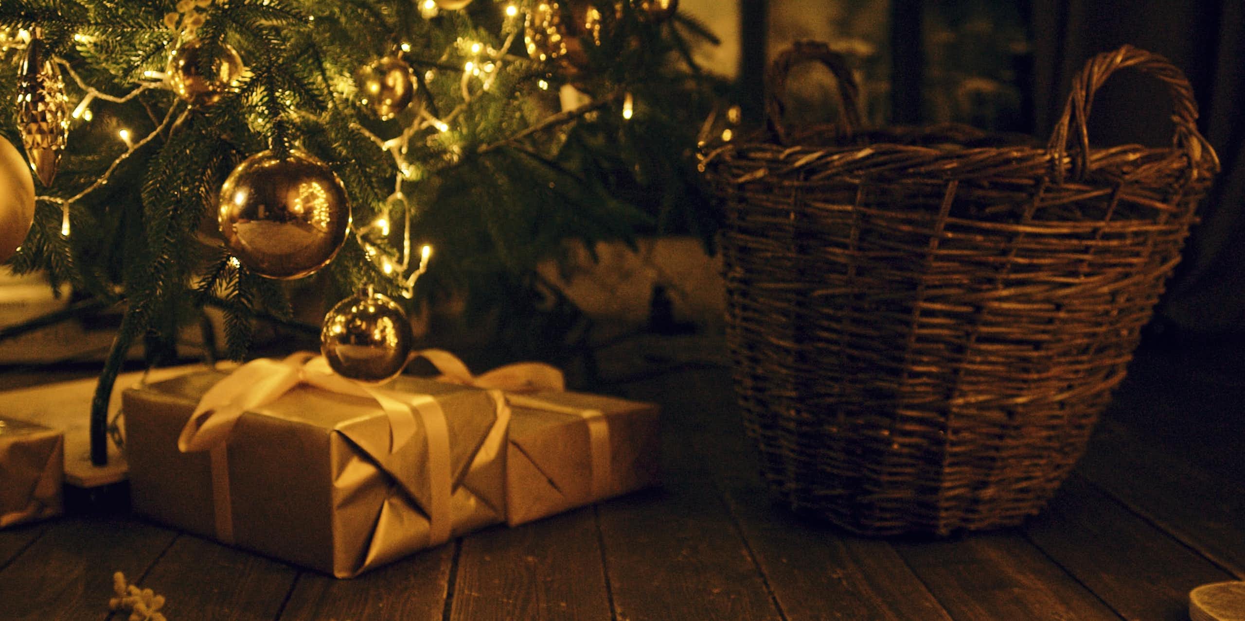 presents at the foot of a christmas tree. the light is golden.