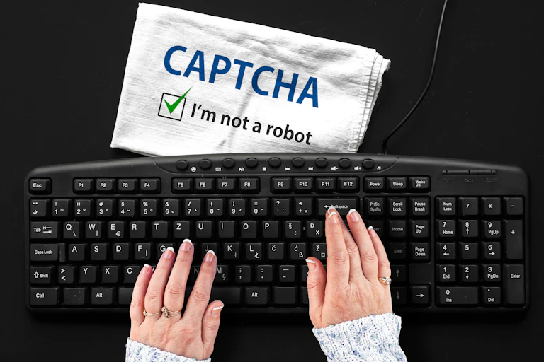 Woman's hands at a keyboard along with a sign saying 'I am not a robot'