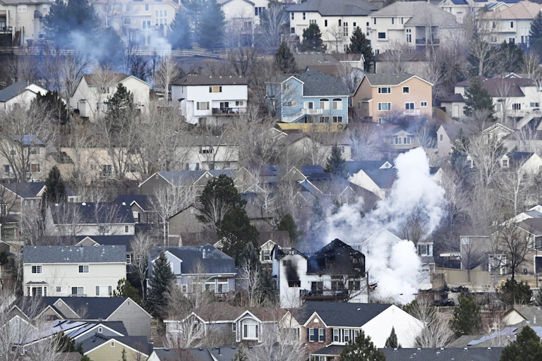 A house smolders in the aftermath of the Marshall fire in Superior, Colorado, on Dec. 31, a day later. Two fires are still evident among a dense neighborhood of two-story homes.