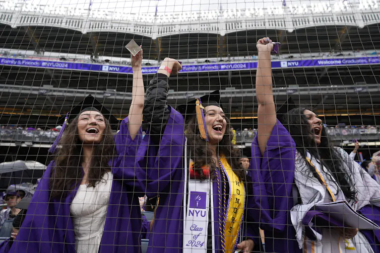 A group of women cheer in a stadium.