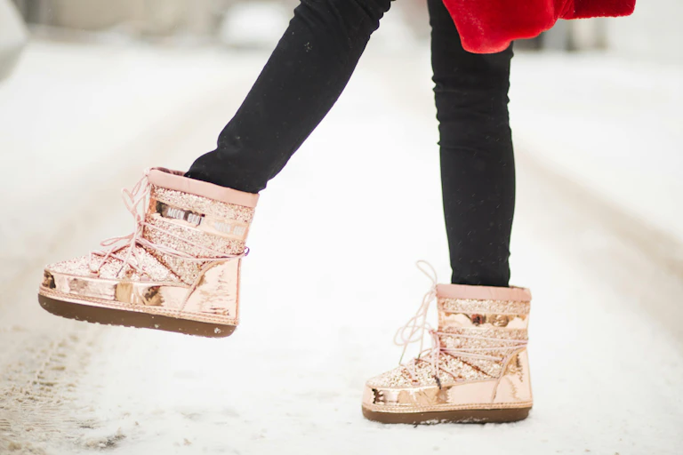 Pink boots seen on a snowy road.