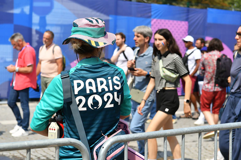 Un bénévole des Jeux Olympiques regarde des supporters.
