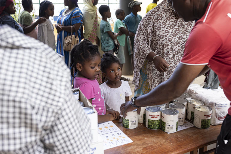 Deux enfants regardent une boîite d'haricots dans une distribution alimentaire à Mayotte.