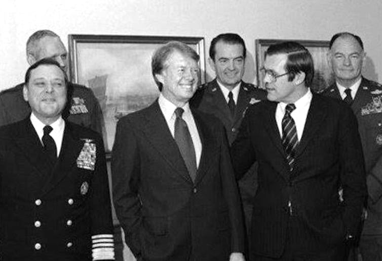 a black and white photograph of five men in military uniform and one man in a business suit