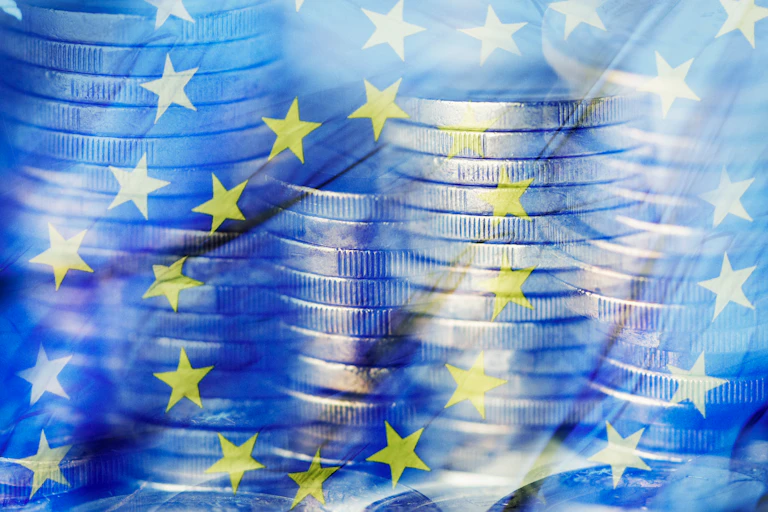 Pièces d'euros empilées sur fond du drapeau de l'UE