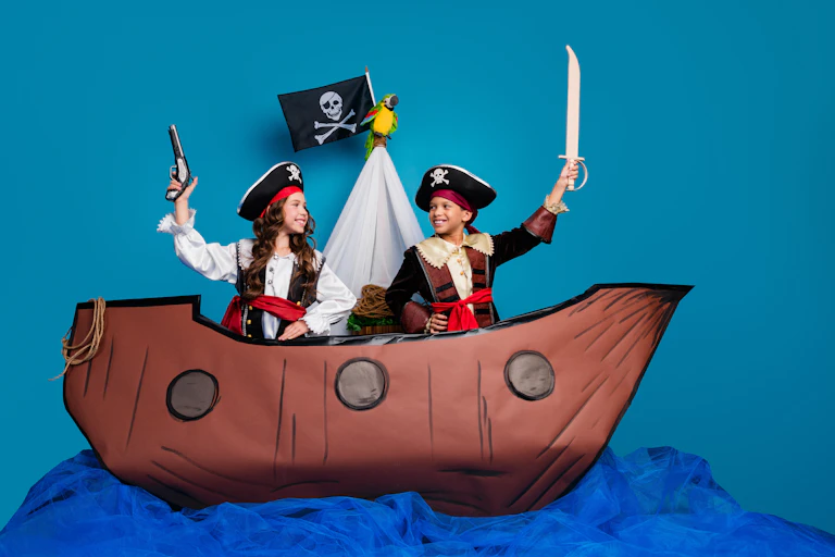 deux enfants, un garçon et une fille, déguisés en pirate sur un faux bateau dans un décor