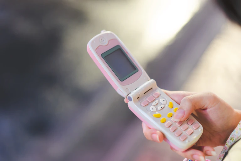 Mano de adolescente con un teléfono antiguo.