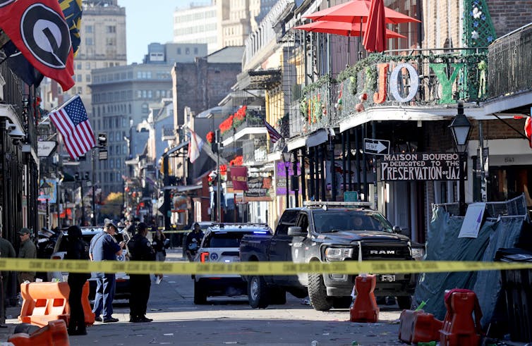 Police patrol a busy street in New Orleans filled with law enforcement vehicles and yellow crime scene tape