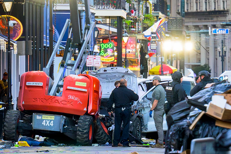 People in police uniforms stand by vehicles and wreckage.