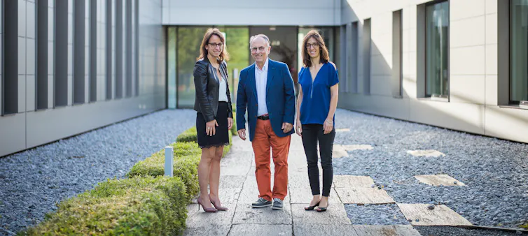 Trois dirigeants d’entreprise devant leur siège social