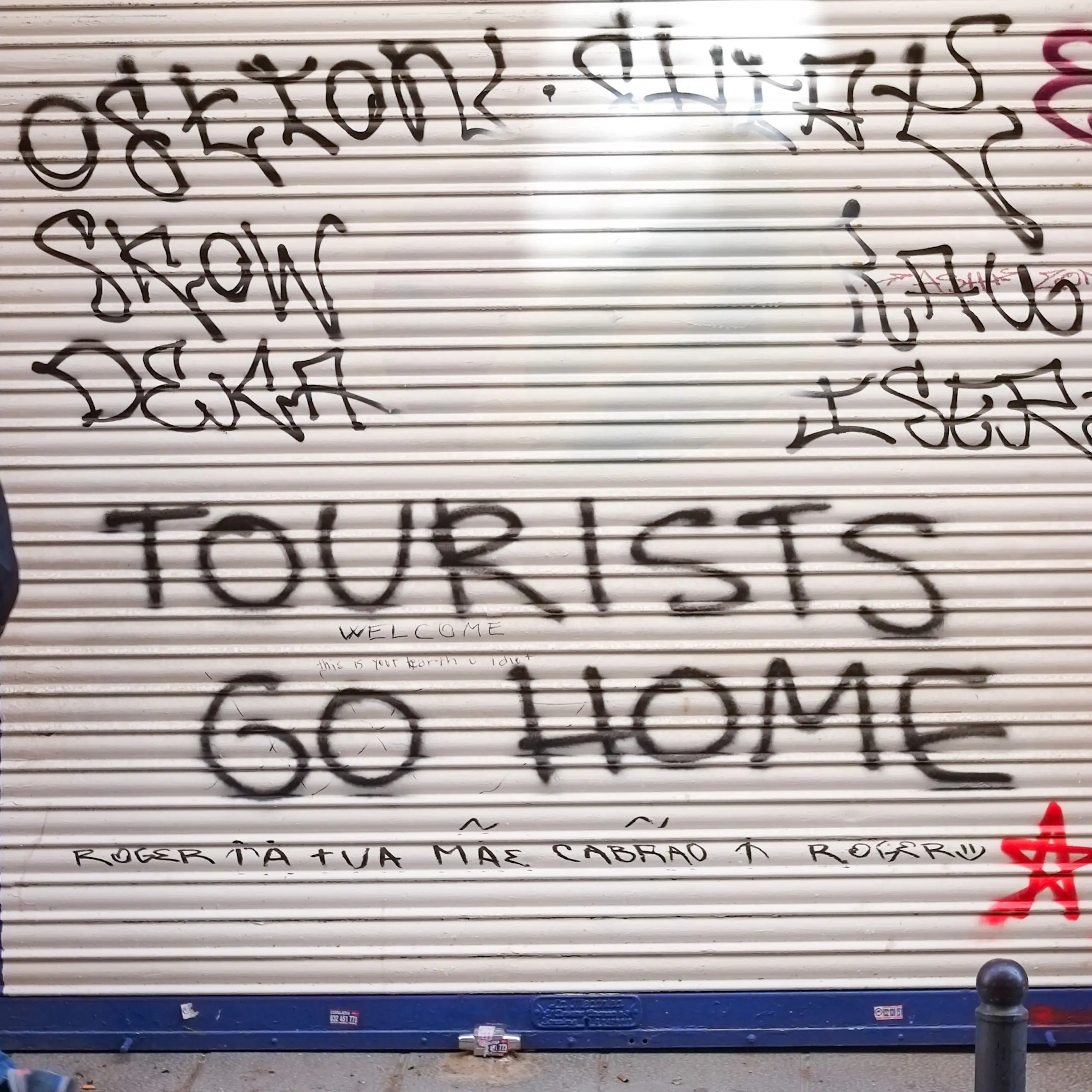 A man walks past a shop shutter with graffiti..