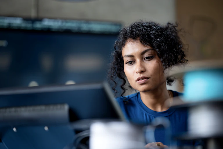 A woman looking at her computer screen at work.