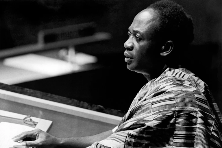 A man wearing Ghanaian traditional attire speaks at a podium.