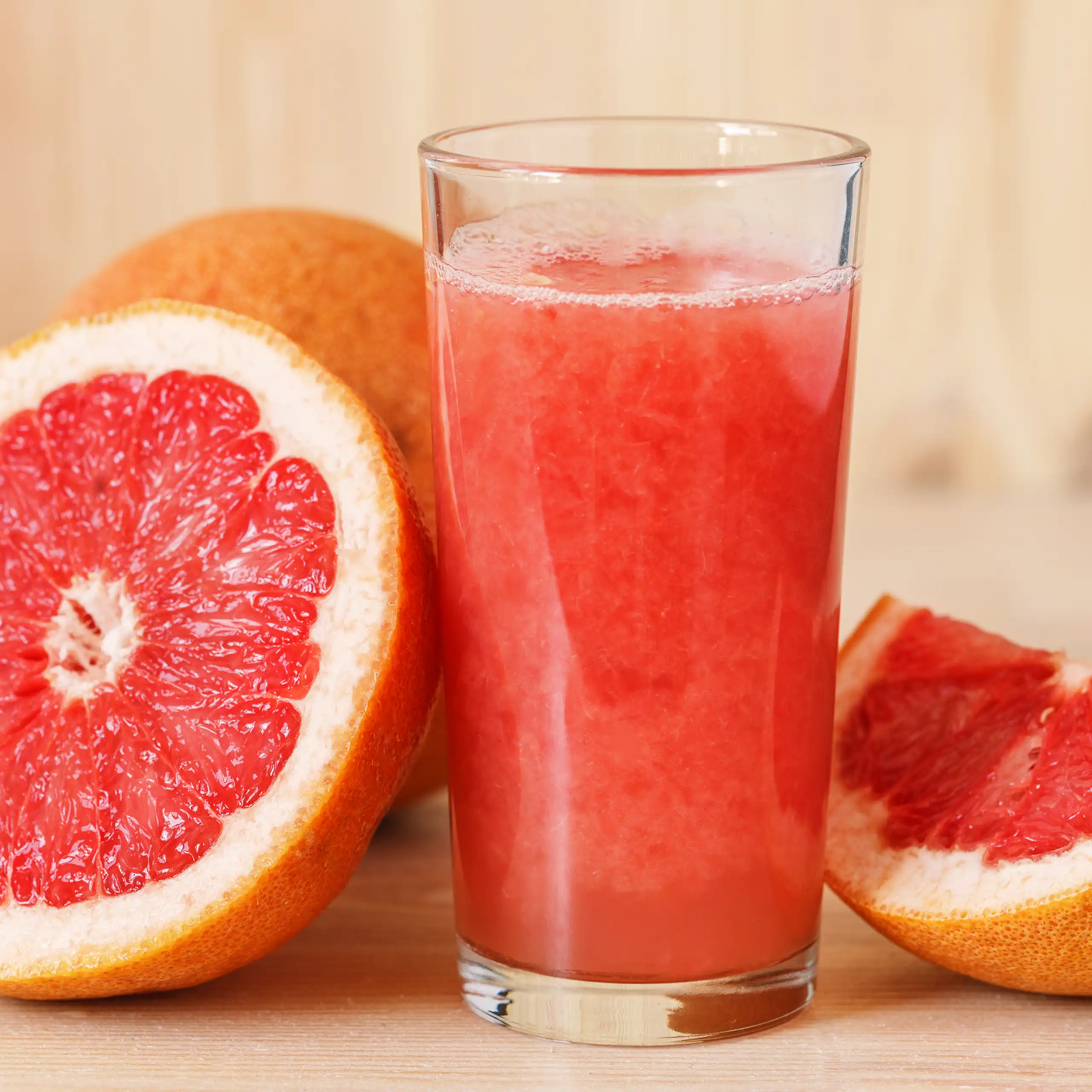 A glass of freshly squeeze grapefruit juice, with grapefruit slices sitting beside it.