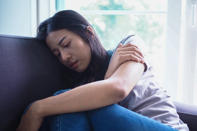 Lonely and sad woman sitting on a sofa.