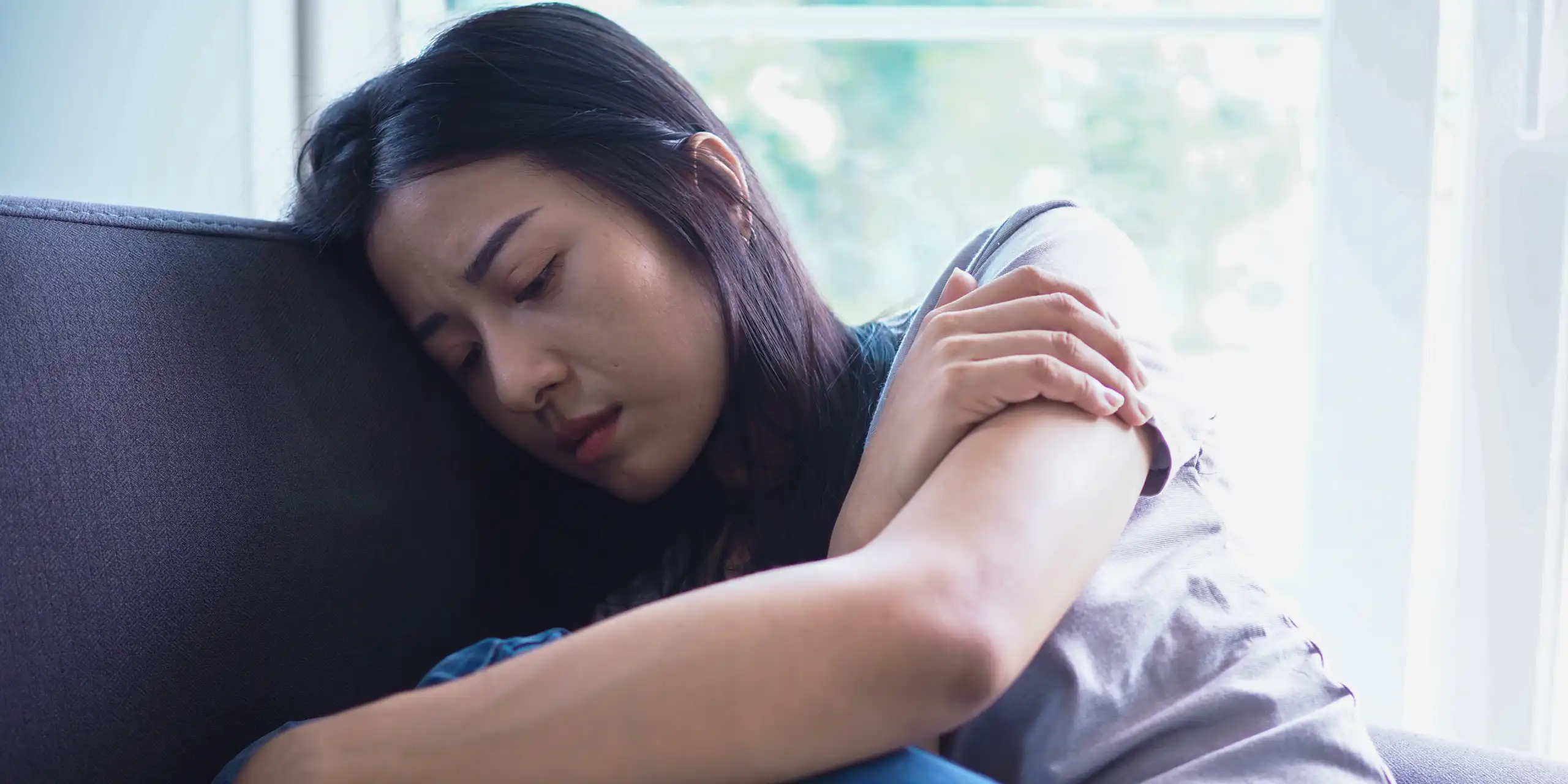 Lonely and sad woman sitting on a sofa.