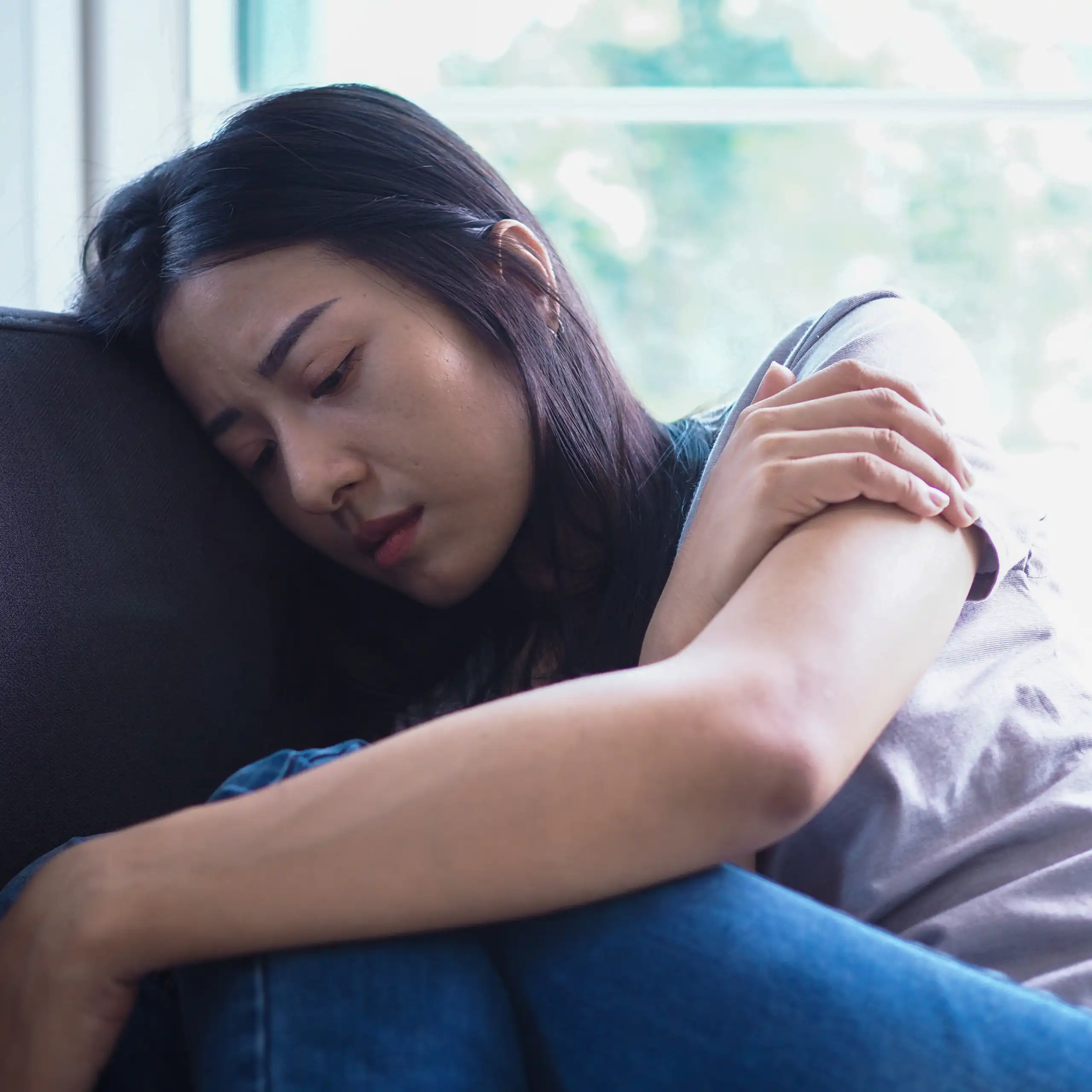 Lonely and sad woman sitting on a sofa.