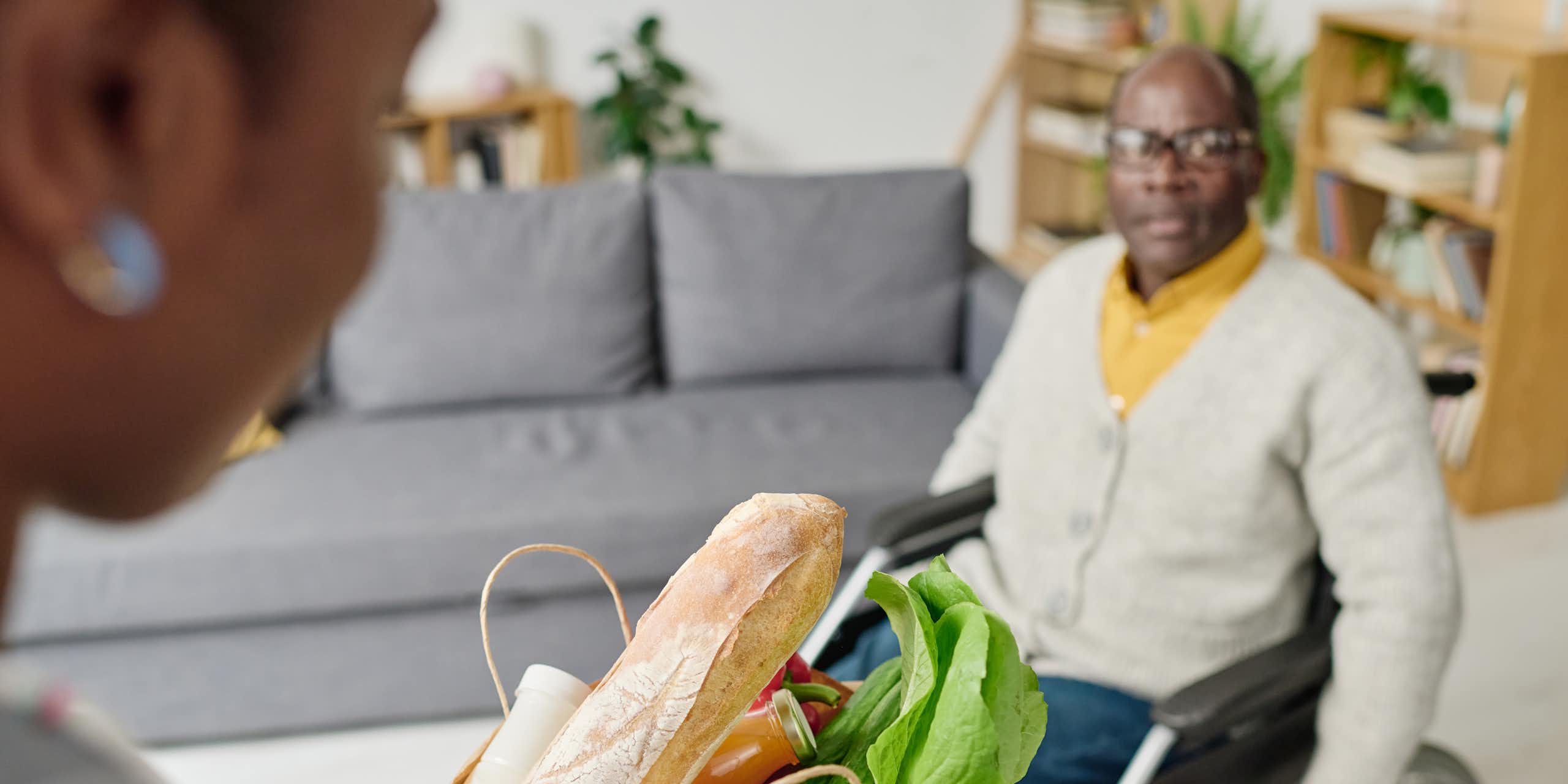 Une femme fait les courses pour son proche en situation de handicap qui se déplace en fauteuil roulant