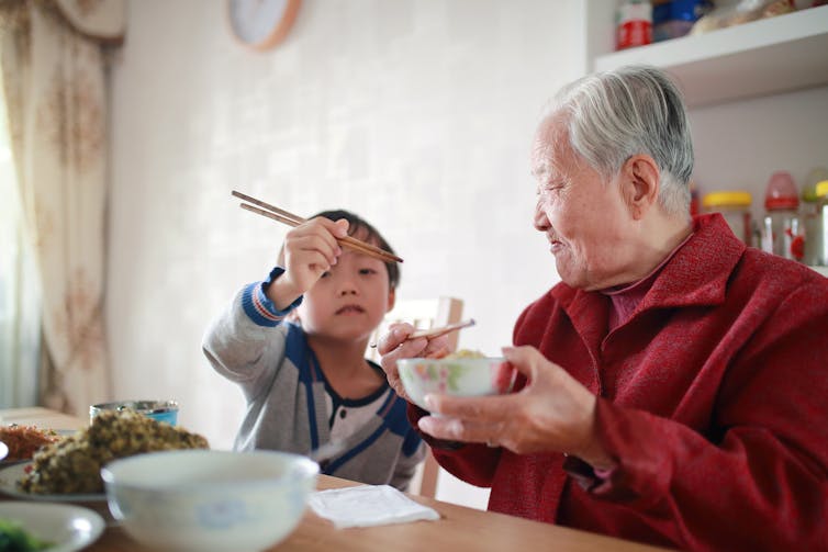 Young Chinese boy and an older man eating lunch