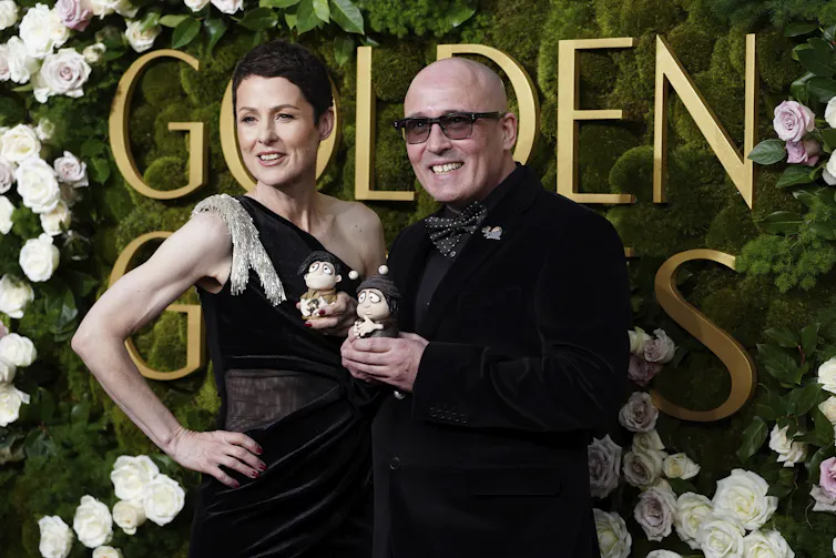 A man holds two small snail figurines.