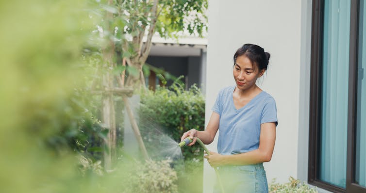 A woman waters her trees in her garden.