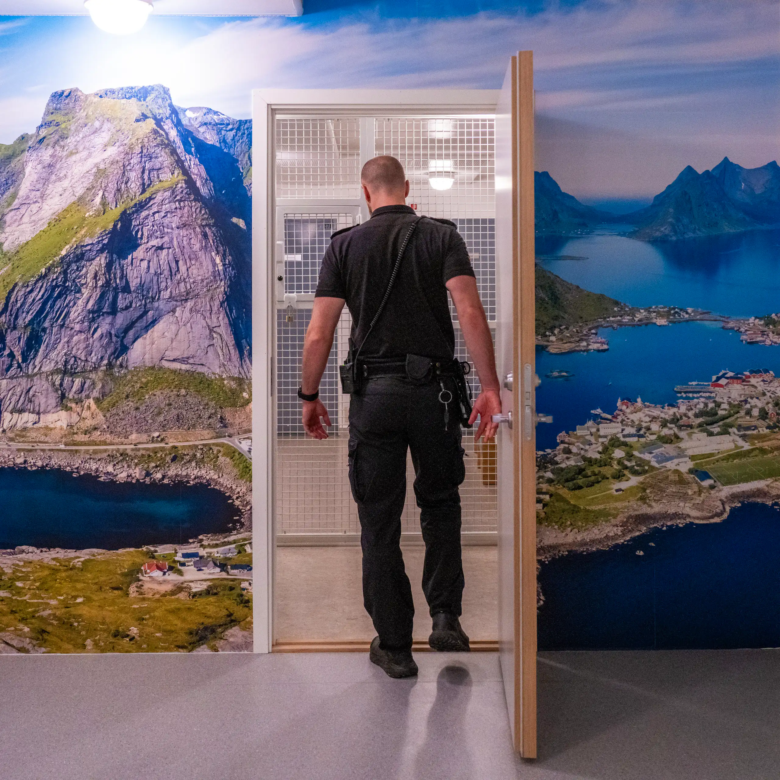 A prison officer walks through a doorway in Norway's Ringerike prison, with a photograph mural of a beautiful nature scene surruonding the doorway