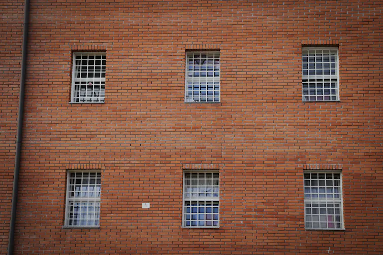 Side view of prison in Gjilan, Kosovo, a red brick wall with six large, barred windows