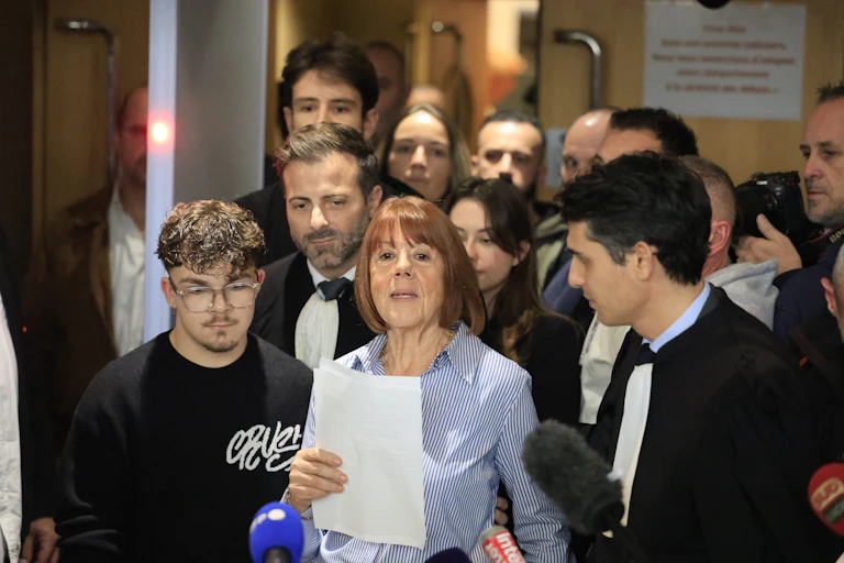 Gisele Pelicot speaking into microphones with a crowd of supporters behind her.