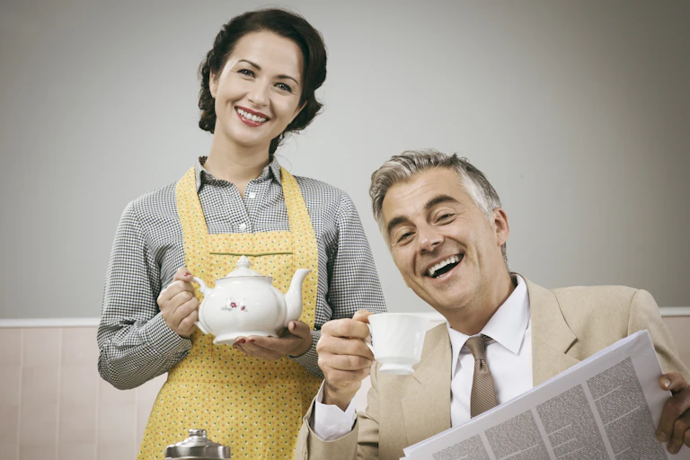 1950s beautiful woman serving tea for breakfast to her smiling husband