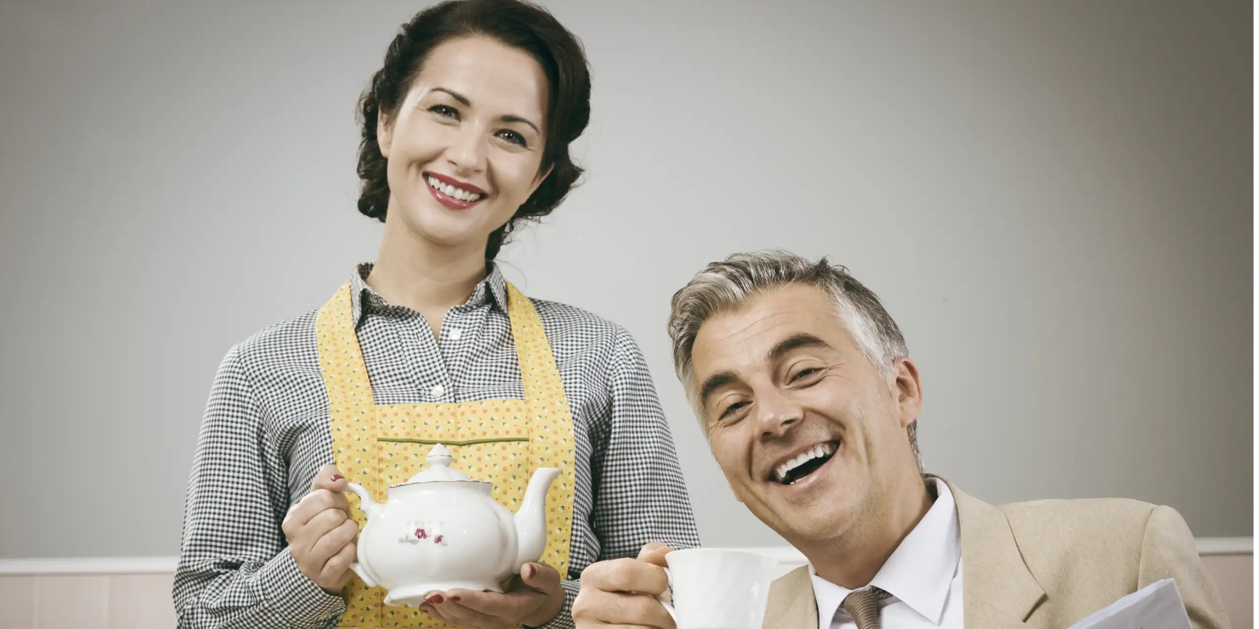 1950s beautiful woman serving tea for breakfast to her smiling husband