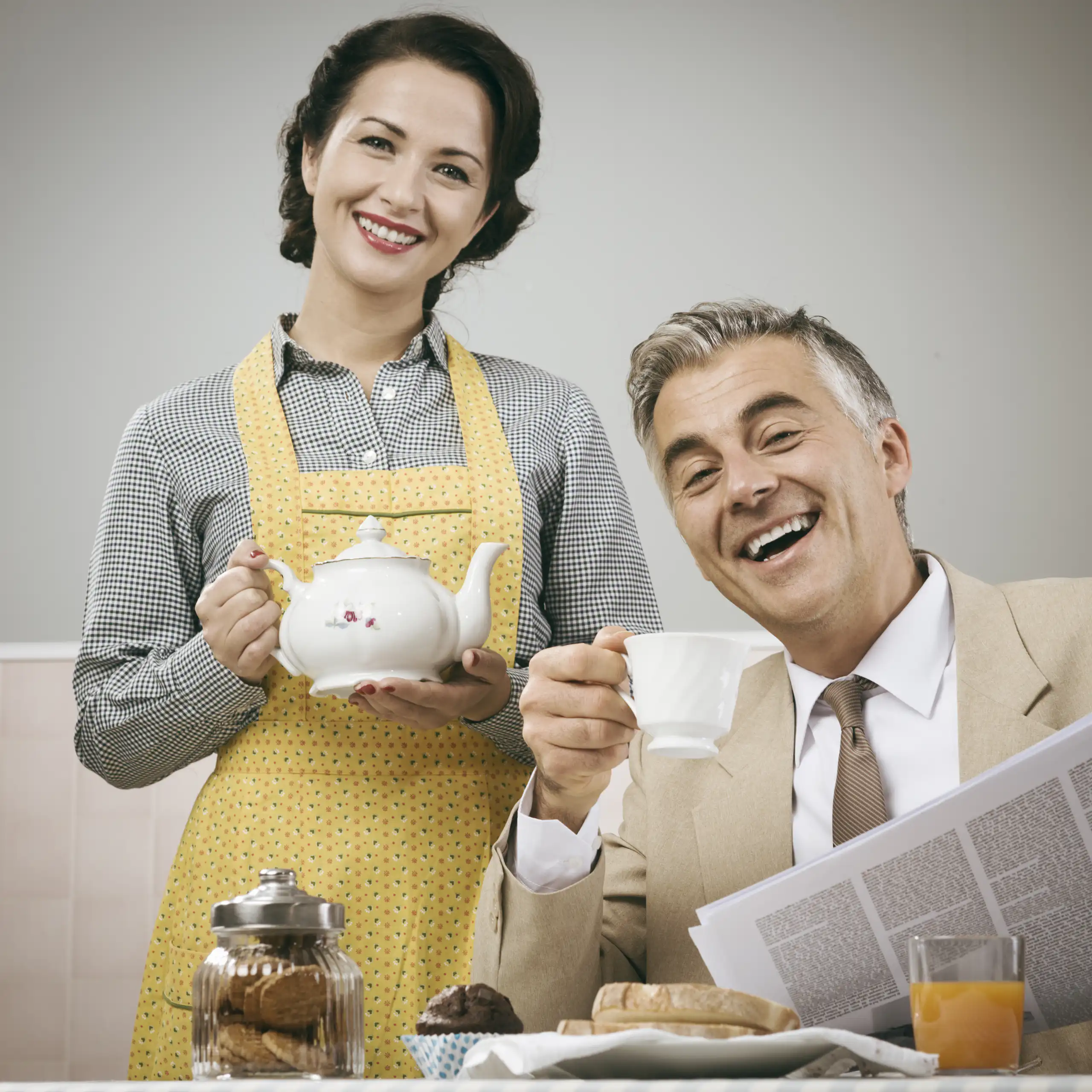 1950s beautiful woman serving tea for breakfast to her smiling husband