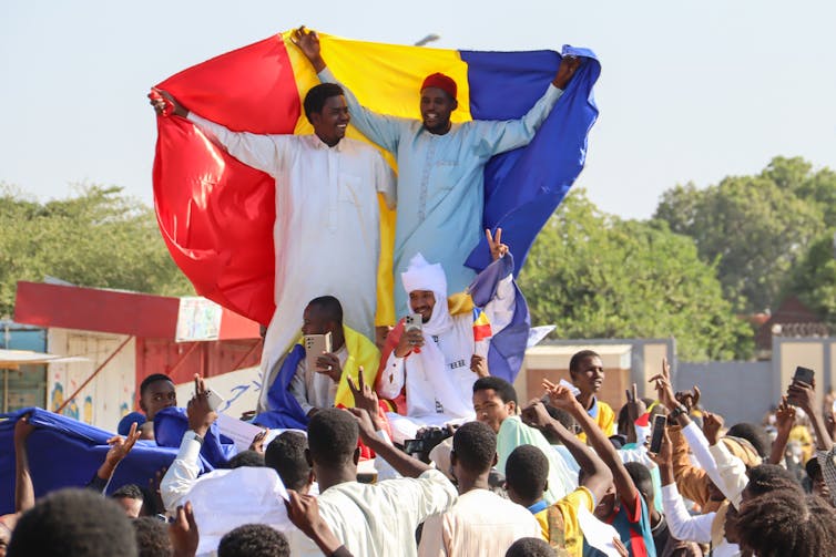 A crowd of Chadians holding flags as they protest.