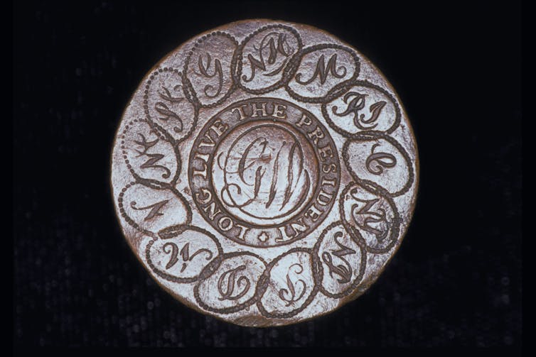 A silver button with the initials 'GW' in the center surrounded by interlocking circles with state initials in each one.