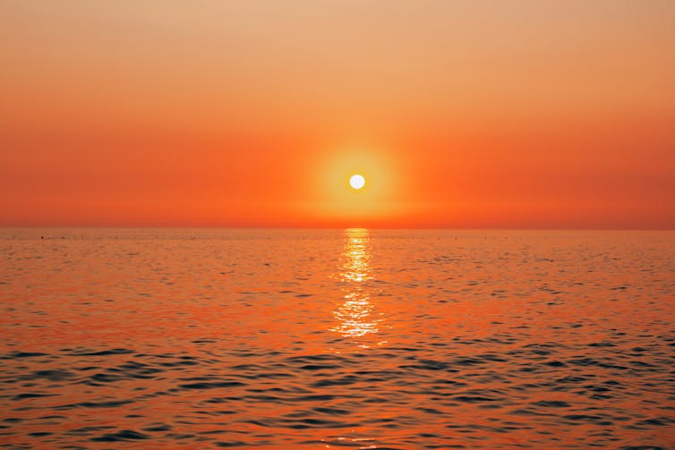 Beautiful landscape - beach on sunset -red and orange sky and sunlight reflecting on sea water.